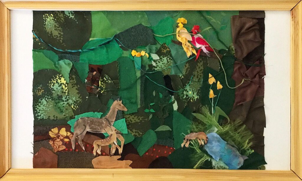 Colored paper is pieced together with a green background, a tree to the right, animals, and two colorful birds.