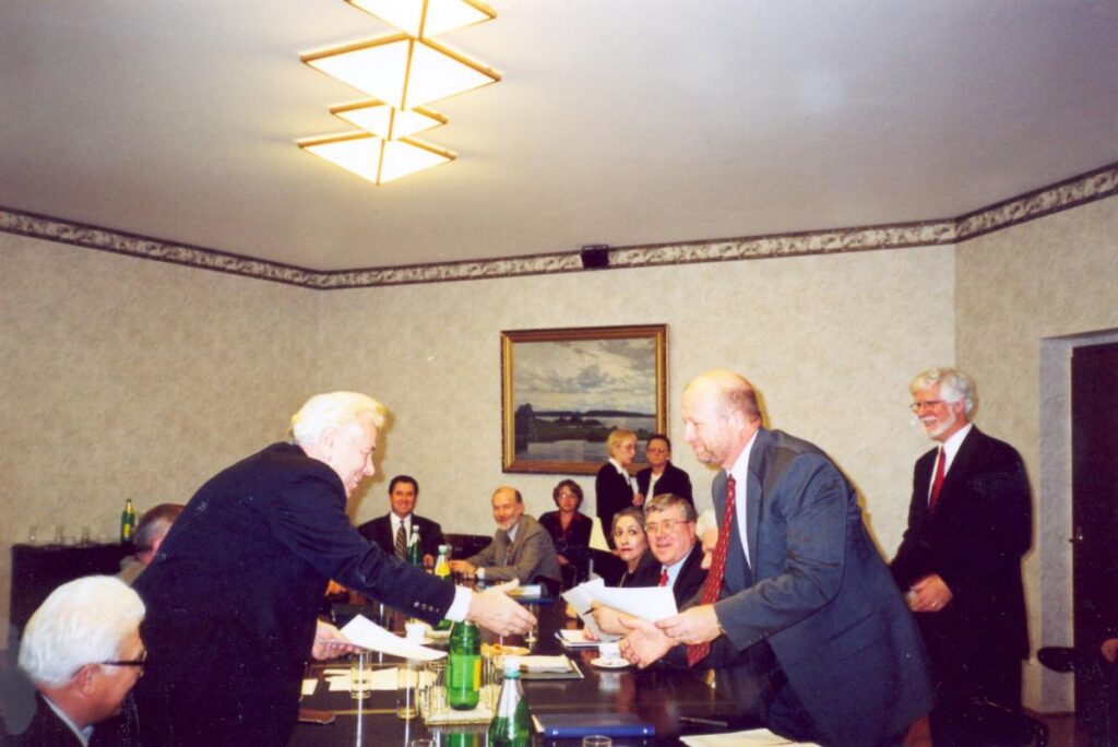 Group in around a conference table, two are shaking hands