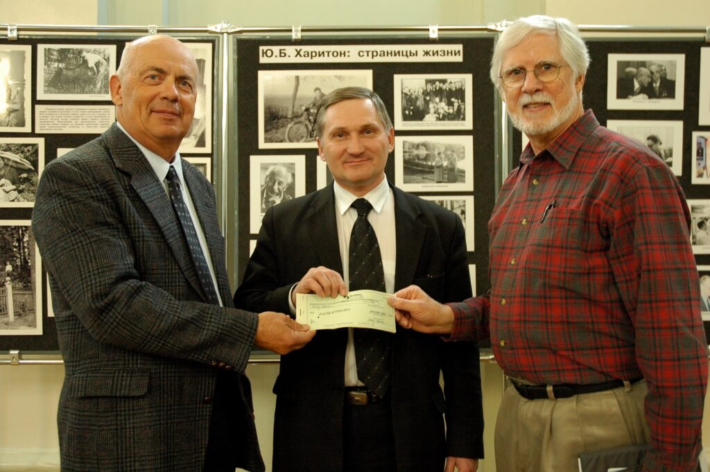 Three men, one holding a check.